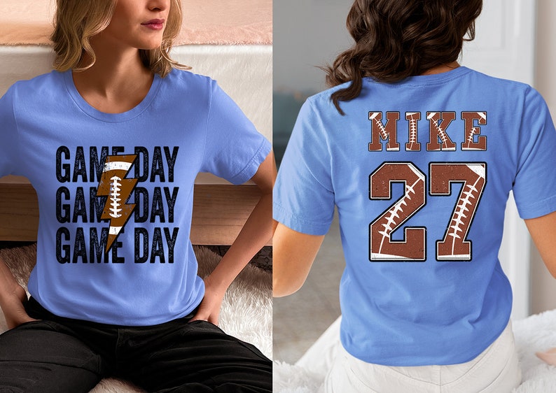 May include: Two light blue t-shirts. One shirt has the text "GAME DAY" repeated three times with a lightning bolt and football graphic. The other shirt has the text "MIKE" and the number "27" with a football graphic.