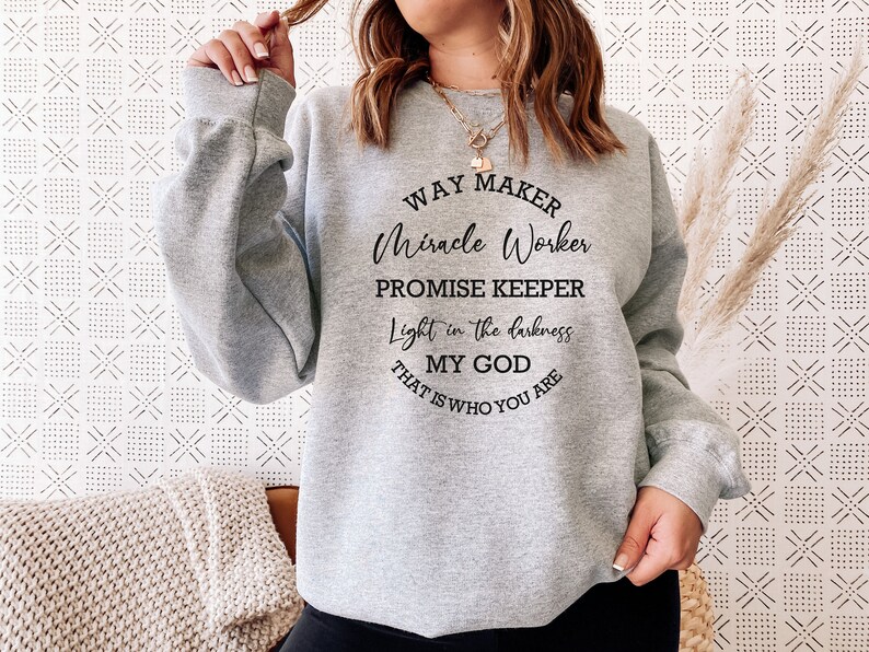 May include: Gray sweatshirt with a black graphic print that reads "Way Maker, Miracle Worker, Promise Keeper, Light in the darkness, My God, That is who you are."