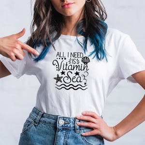 May include: White t-shirt with a black graphic that says "All I need is Vitamin Sea". The graphic includes a seashell, a starfish, and a wave.