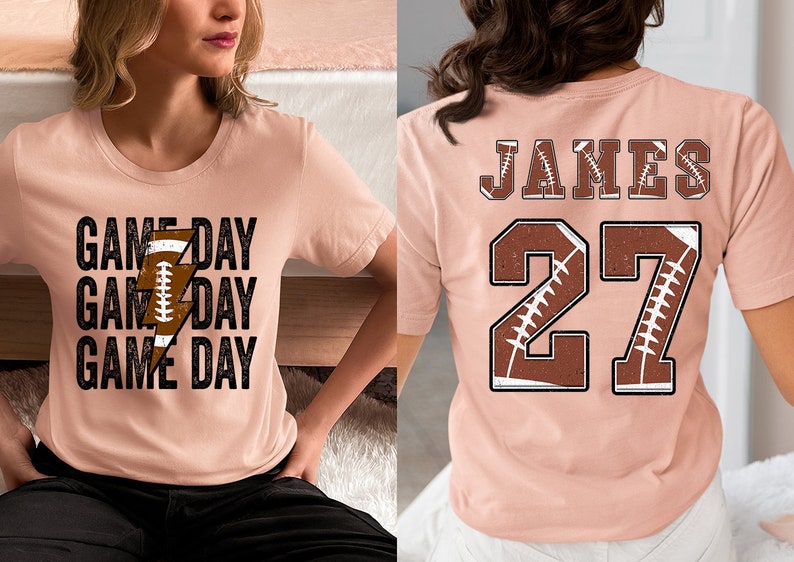 May include: Two pink t-shirts with a football theme. One shirt has the text "GAME DAY" repeated three times with a football and lightning bolt graphic. The other shirt has the name "JAMES" and the number "27" with a football graphic.