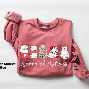 May include: A heather scarlet red sweatshirt with a Christmas design featuring five cats wearing festive attire. The cats are lined up and the text "merry christmas" is printed below them.