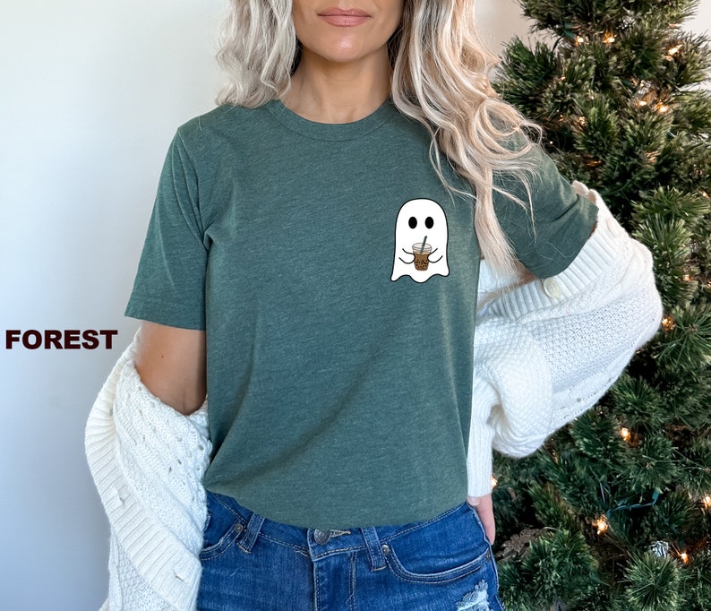 Puede incluir: Una camiseta verde con un gr&aacute;fico de fantasma blanco sosteniendo una taza de caf&eacute;. El fantasma tiene dos ojos y una peque&ntilde;a sonrisa. La camiseta est&aacute; hecha de un material suave y c&oacute;modo.