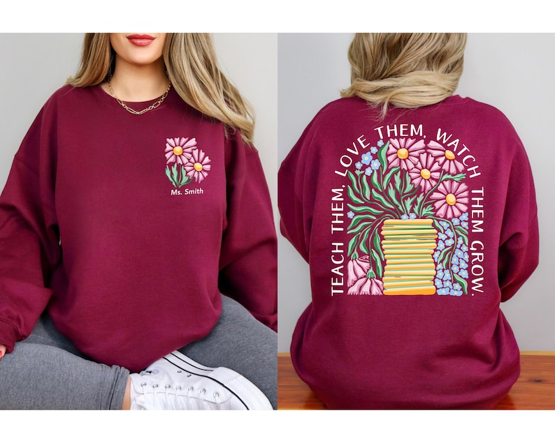 May include: Burgundy sweatshirt with a floral design. The front features a small floral graphic with the name "Ms. Smith." The back displays a larger floral arrangement with the text "Teach them, love them, watch them grow."