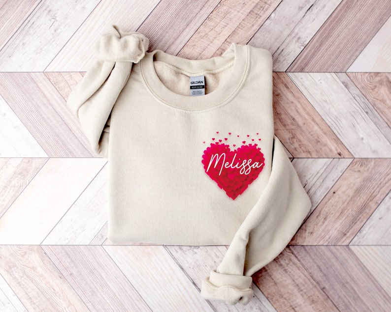 May include: A cream colored sweatshirt with a heart made of pink hearts that says "Melissa" on it.