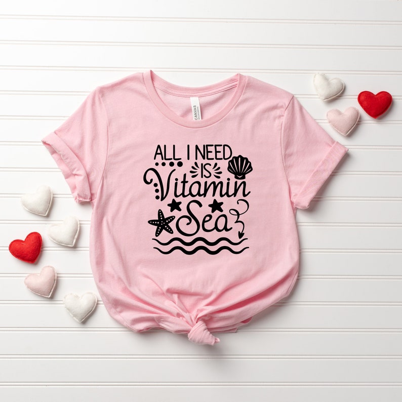 May include: Pink t-shirt with a black graphic that says "All I need is Vitamin Sea" with a seashell, starfish, and anchor.