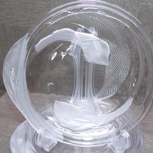 May include: A clear glass decorative bowl with a frosted leaf and feather design. The bowl has a rounded shape with a wide opening and sits on a clear base. The frosted design adds a delicate touch to the piece.