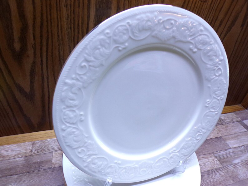 Pu&ograve; includere: Piatto in ceramica bianca con bordo a rilievo con motivi floreali e volute. Il piatto ha una superficie liscia e lucida ed &egrave; di forma leggermente ovale. Il bordo decorativo aggiunge un tocco di eleganza alle stoviglie.
