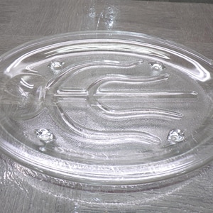 May include: Clear glass oval serving platter with a divided design. The platter has a raised rim and integrated handles on each side. The interior features a central divider and decorative wave-like patterns.