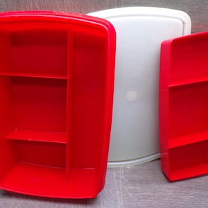 May include: Two rectangular red plastic storage containers with internal dividers and a single translucent white lid. The larger container features a vertical divider and two horizontal shelves, while the smaller container has two horizontal shelves.