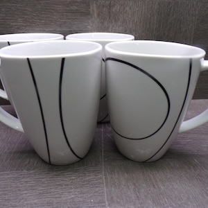 May include: A set of four white ceramic mugs featuring a smooth, tapered silhouette and a handle on the side. Each mug is decorated with thin, black, curved lines that create abstract patterns across the exterior surface of the white vessels.
