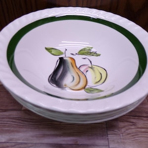 May include: White ceramic bowl with a green rim and a pear design. The bowl has a scalloped edge and a painted illustration of a pear and apple with green leaves. The bowl is stacked on top of another bowl.