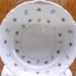 May include: White porcelain plate with a scalloped edge, decorated with small pink roses and gray leaves. A silver-colored ring encircles the center of the plate. This vintage plate is a charming addition to any table setting.
