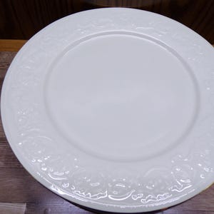 Pu&ograve; includere: Un piatto da cena in ceramica bianca con un motivo floreale decorativo in rilievo sul bordo. Il piatto &egrave; rotondo e ha una superficie liscia e lucida. Il piatto misura circa 30 cm di diametro.