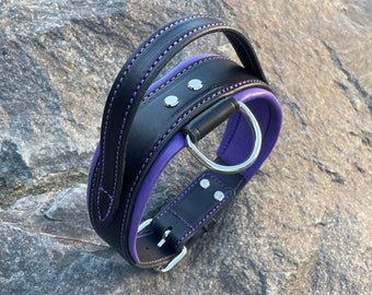 May include: A black leather dog collar with a purple lining and a silver D-ring. The collar has a handle on top.