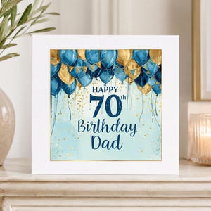 May include: A square greeting card featuring a light blue background with gold glitter accents and a cluster of dark blue and gold balloons at the top. The text reads Happy 70th Birthday Dad in dark blue lettering centered on the card.