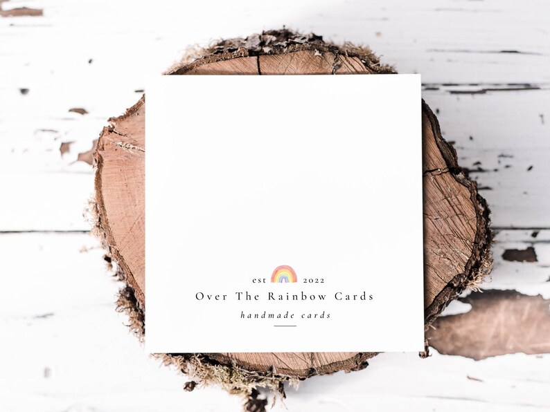 以下が含まれることがあります： 白地に「Over The Rainbow Cards」と「handmade cards」という黒い文字が書かれたカード。文字の上に小さな虹のグラフィックが描かれている。虹のグラフィックの上に「est 2022」という黒い文字が書かれている。