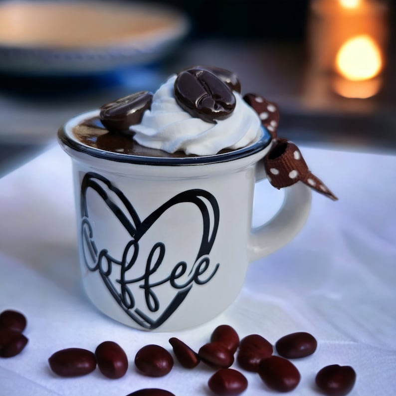 May include: A white ceramic mug with a black heart and the word "coffee" written inside. The mug is filled with chocolate mousse topped with whipped cream and chocolate coffee beans.