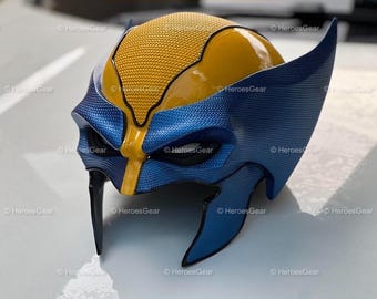 May include: A blue and yellow plastic mask with a textured surface. The mask has a yellow top and a blue bottom with a yellow stripe down the center. The mask has a raised design on the forehead and around the eyes.