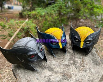 Könnte beinhalten: Drei Wolverine-Masken, eine schwarze mit roten Augen, eine gelbe und schwarze mit blauen Augen und eine gelbe und schwarze mit violetten Augen.
