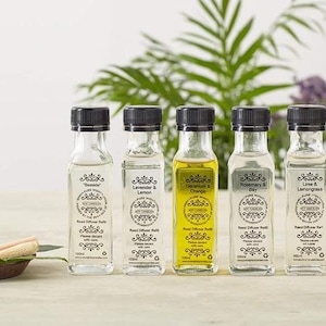 May include: Set of eight 100 ml glass bottles with black caps and labels. The bottles contain reed diffuser refills with various scents, including Lavender & Lemon, Geranium & Orange, Rosemary & Bay, Lime & Lemongrass, and Strawberry & Rhubarb.