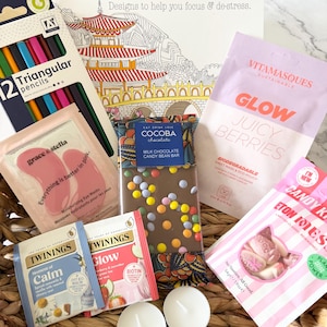 May include: A gift basket containing The Colouring Book of Mindfulness, a pack of 12 triangular pencils, a Cocoba milk chocolate candy bean bar, Vitamasques Glow sheet mask, Grace & Stella eye masks, Twinings tea bags, Candy Kittens Eton Mess sweets, and two white tea light candles.