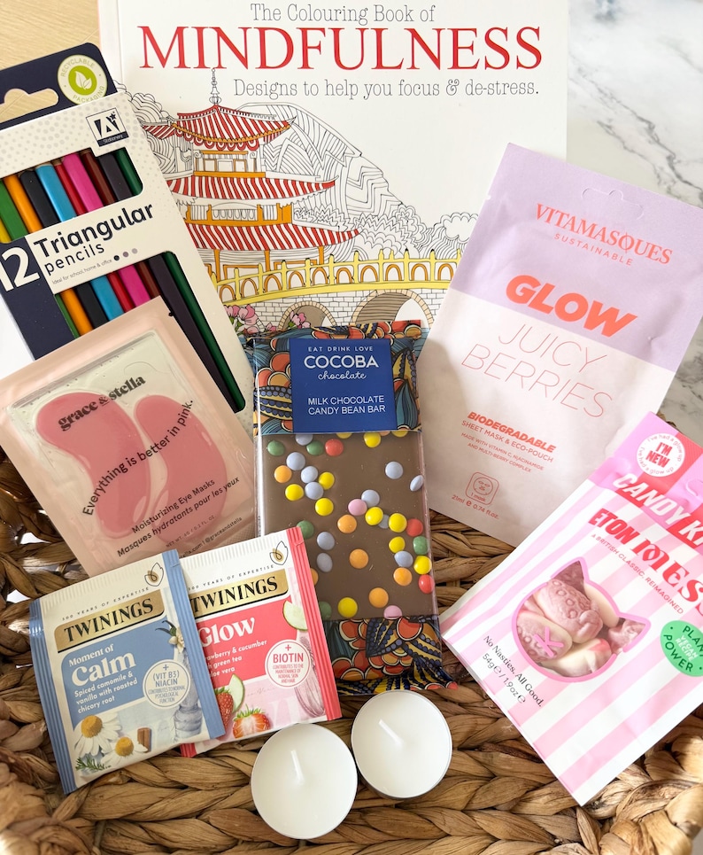 May include: A gift basket containing The Colouring Book of Mindfulness, a pack of 12 triangular pencils, a Cocoba milk chocolate candy bean bar, Vitamasques Glow sheet mask, Grace & Stella eye masks, Twinings tea bags, Candy Kittens Eton Mess sweets, and two white tea light candles.