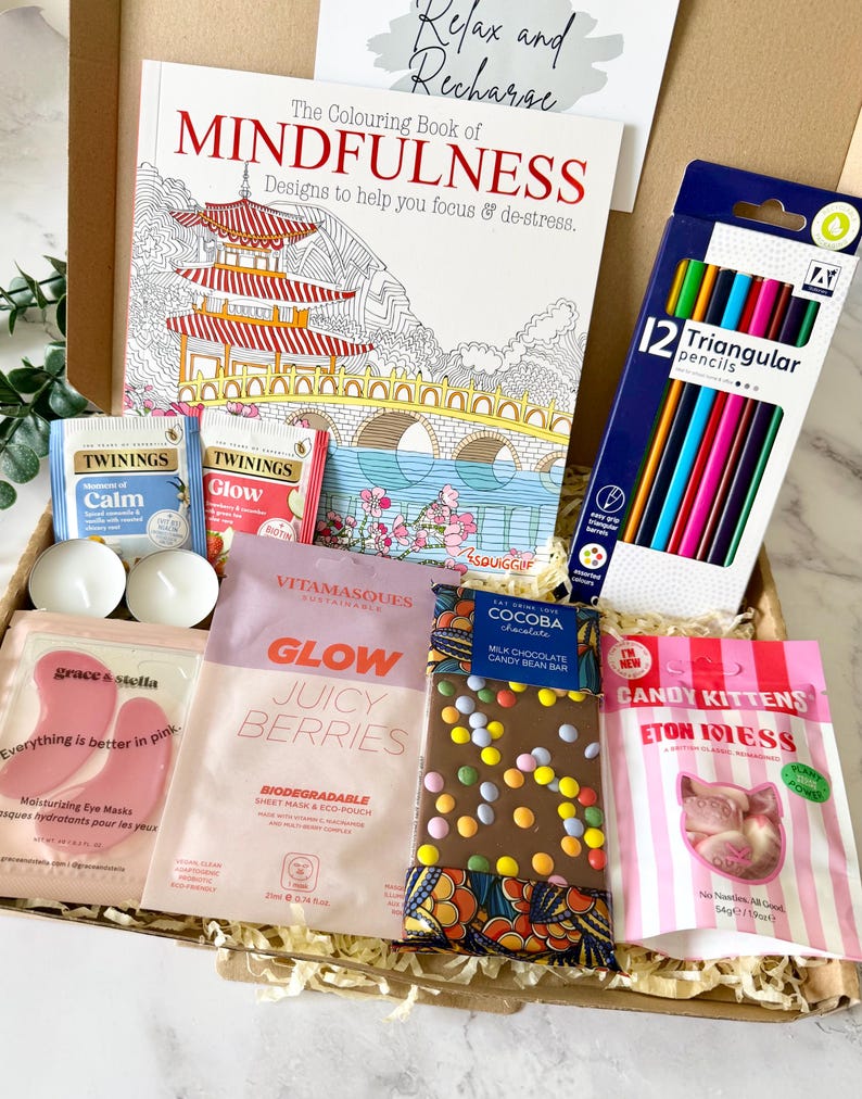 May include: A gift box containing The Colouring Book of Mindfulness, a pack of 12 triangular pencils, two Twinings tea bags, two tea light candles, pink Grace & Stella eye masks, a Vitamasques sheet mask, a Cocoba chocolate bar, and Candy Kittens.
