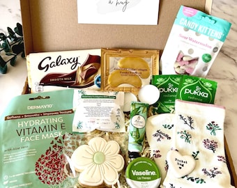 May include: A gift box containing a Galaxy chocolate bar, Candy Kittens sour watermelon candy, a gold collagen eye mask, Pukka tea, a DermaV10 Vitamin E face mask, a flower-shaped cookie, aloe hand cream, Vaseline lip therapy, and floral socks.