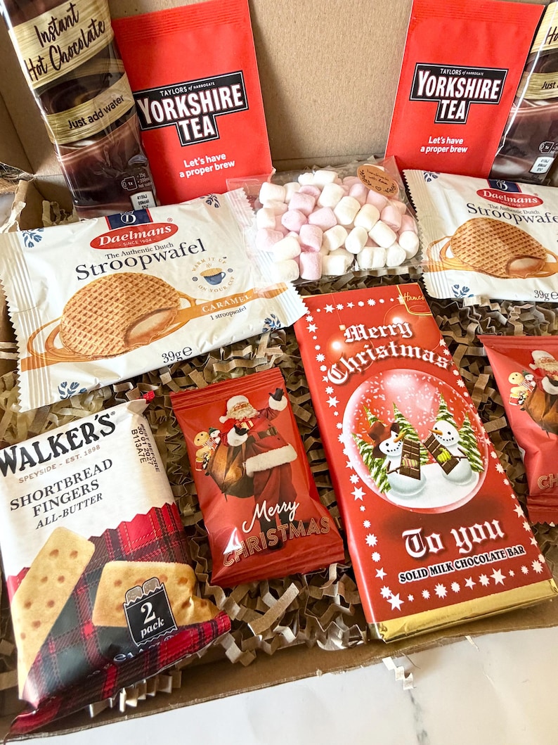 May include: A gift box containing two Taylors of Harrogate Yorkshire Tea bags, two Daelmans caramel stroopwafels, a Walker's shortbread fingers pack, a bag of mini marshmallows, a Merry Christmas chocolate bar, and hot chocolate mix.