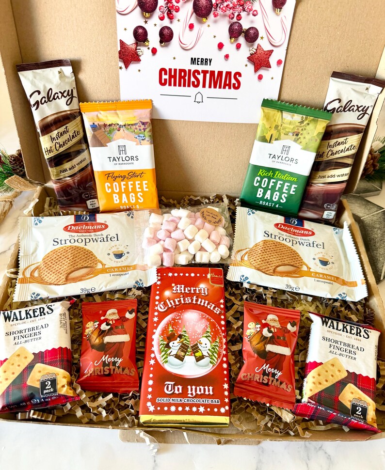 May include: A Christmas gift box containing two Galaxy instant hot chocolate sachets, Taylors of Harrogate coffee bags, two Daelmans stroopwafels, a bag of mini marshmallows, two Walkers shortbread finger packs, and a Merry Christmas chocolate bar.