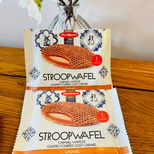 May include: Two individual Daelmans Stroopwafel packages featuring a graphic of a round, grid-patterned waffle with a caramel filling. The white packaging displays the text Stroopwafel, Caramel Waffles, and a red circle with 1 Waffle.