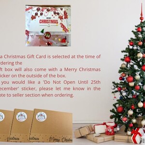 May include: A Christmas tree decorated with red, gold, and silver ornaments stands next to three brown cardboard gift boxes. Each box features a circular sticker and the text Merry Christmas printed along the bottom edge.