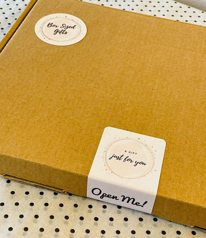 May include: A brown cardboard box with two stickers. One sticker says "Box Sized Gifts" in a circular design. The other sticker says "A Gift Just For You" and "Open Me!" in a rectangular design.