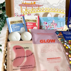 May include: A gift box containing a Mindfulness coloring book, Twinings Moment of Calm and Glow tea bags, two white tea light candles, Grace & Stella pink eye masks, a Vitamasques Juicy Berries sheet mask, and a Cocoba milk chocolate bar.