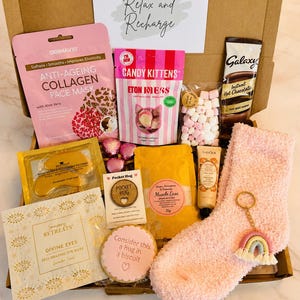 our hug in a box - includes pick cosy socks, hug biscuit, candy kitten sweets, hug token, rainbow keyring, self heating eye mask, gold collagen under eye masks, face sheet mask, hot chocolate sachet, mini marshmallows, bath salts, Handcream….ready to shit direct to the recipient