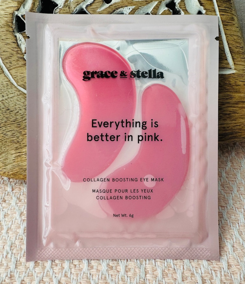 May include: A rectangular pink packet containing two pink collagen boosting eye masks. The text reads grace & stella, Everything is better in pink., COLLAGEN BOOSTING EYE MASK, MASQUE POUR LES YEUX COLLAGEN BOOSTING, and Net Wt. 6g.