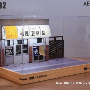 May include: A miniature diorama of a Japanese tofu shop, "藤原豆腐店", in a clear display case with a wooden base. The shop has a white awning with the text "手づくりの店" and "とうふ 油あげ" in Japanese. The diorama is 28 cm x 15.5 cm x 16 cm.