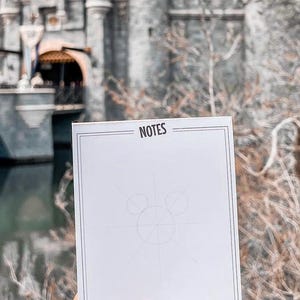 May include: A white notepad with a black border and the word "NOTES" printed at the top. The notepad has a faint pencil drawing of Mickey Mouse's head on it.