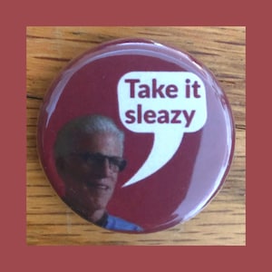 Könnte beinhalten: Ein roter Knopf mit einer weißen Sprechblase, auf der "Take it sleazy" steht. Im Hintergrund ist ein Foto eines Mannes mit Brille zu sehen.