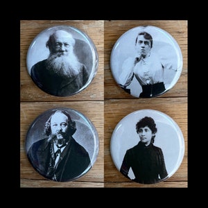 May include: Four black and white portraits of people on round buttons. The portraits are of a man with a beard, a woman with glasses, a man with a beard, and a woman with long hair.