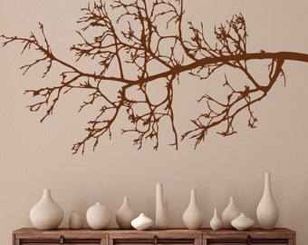 Könnte beinhalten: Eine braune Silhouette eines kahlen Astes mit vielen Zweigen, montiert an einer hellbeigen Wand über einem Holzkasten mit weißen Keramikvasen.