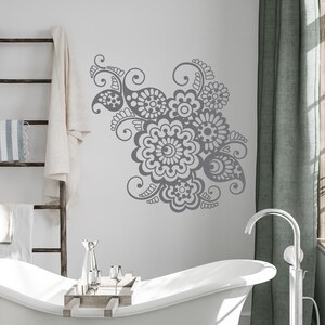 Può includere: Una vasca da bagno bianca con un adesivo murale floreale grigio sopra. La vasca da bagno ha un vassoio di legno con bicchieri d'argento sopra. Il bagno ha un pavimento piastrellato grigio e un rubinetto a pavimento argentato.