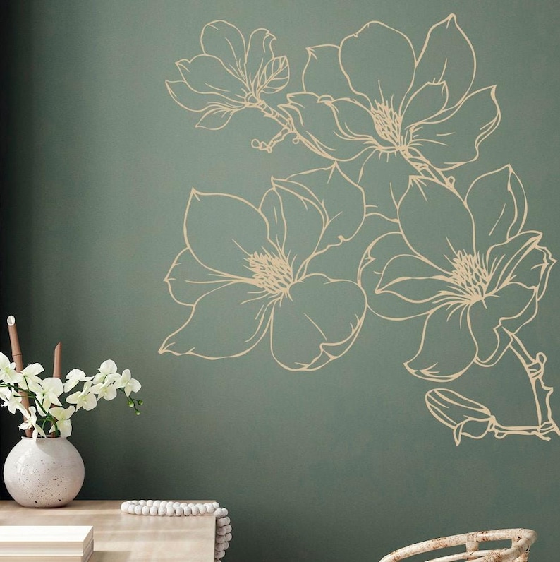 May include: A wall decal featuring a cluster of stylized magnolia flowers in a cream color against a teal green background.
