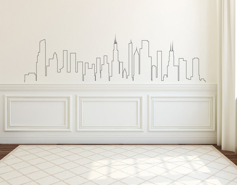 K&ouml;nnte beinhalten: Eine wei&szlig;e Wand mit einer schwarzen Umrandung einer Skyline, mit hohen Geb&auml;uden und Wolkenkratzern. Die Wand hat wei&szlig;e Wandverkleidung mit einem wei&szlig;en Teppich davor.