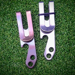 May include: Two metal money clips with bottle opener and key ring features. One clip is silver and the other is a bronze colour.