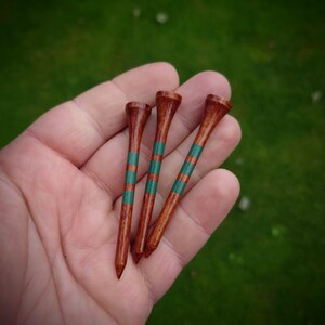 May include: Three wooden golf tees with green and brown stripes.