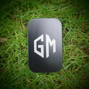 May include: A black rectangular box with a white "GM" logo in a hexagonal shape.
