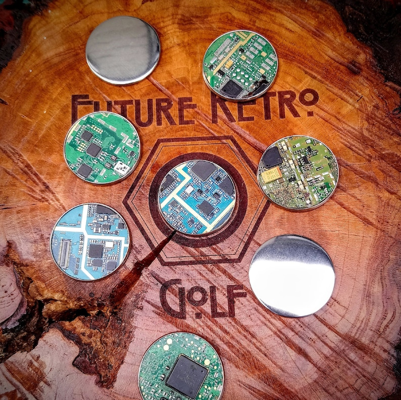 May include: Eight round, silver-colored, circuit board-style golf ball markers with the text "Future Retro Golf" on a wooden surface.