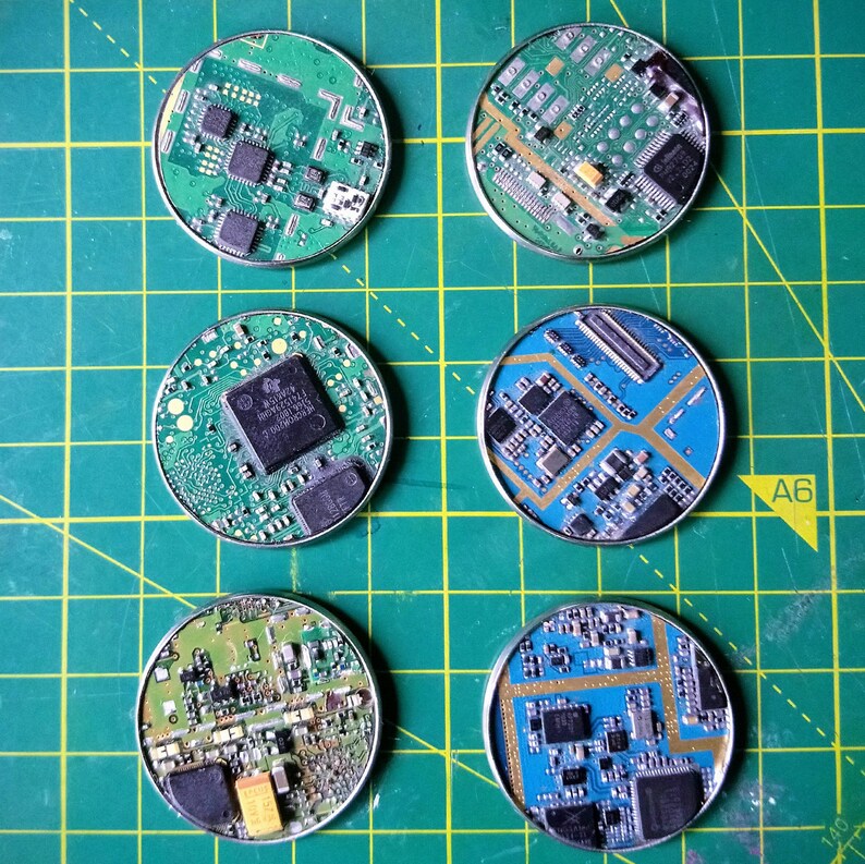 May include: Six round, green and blue circuit boards with gold-colored components. The circuit boards are arranged in a circle on a green grid.