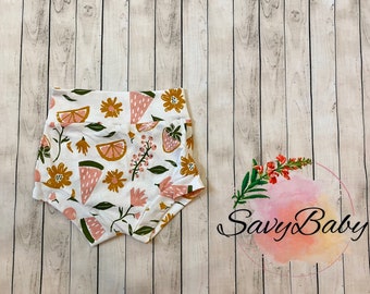 May include: White cotton baby bloomers with a colorful print of lemons, watermelon slices, strawberries, and flowers. The bloomers have a ruffled edge.